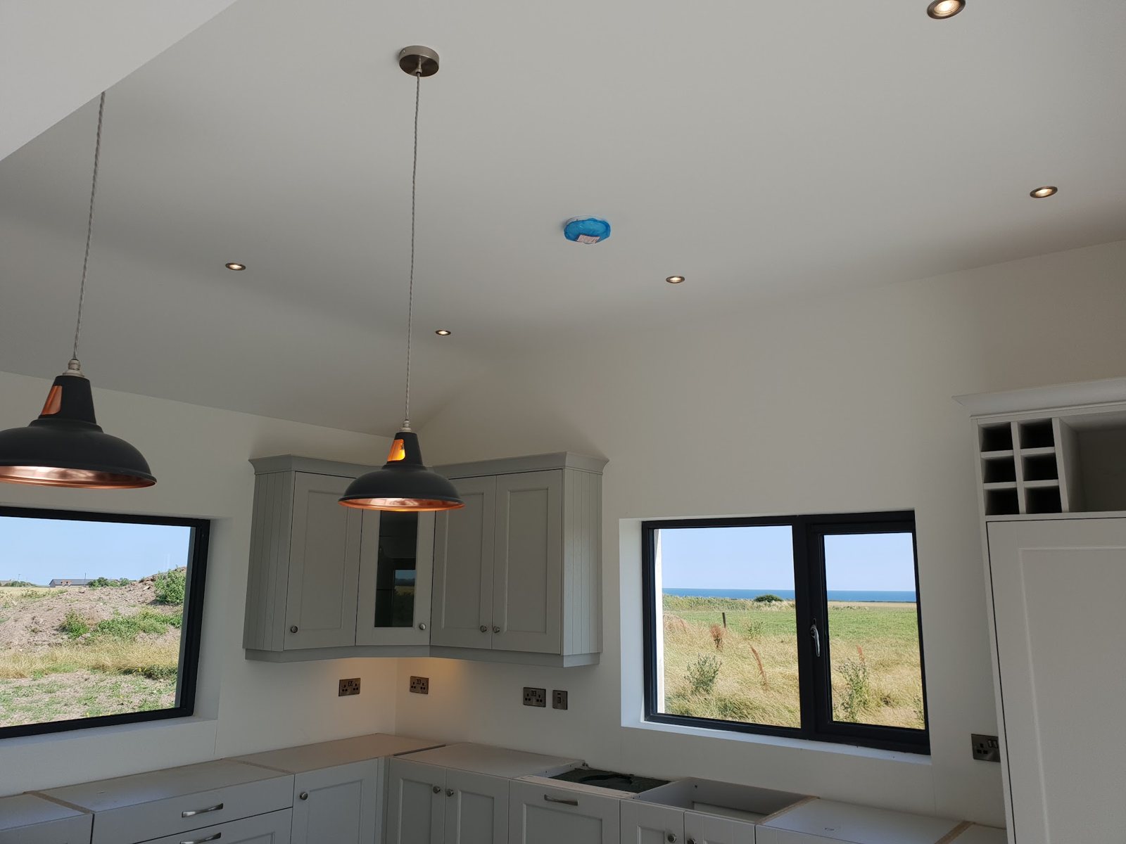 A finished kitchen with copper pendant lights