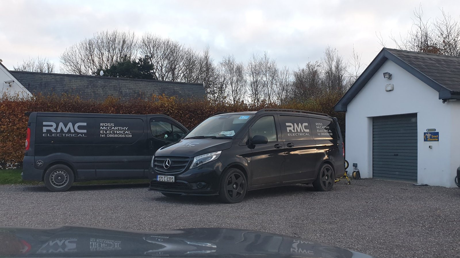 Two black RMC Electrical vans parked outside a house