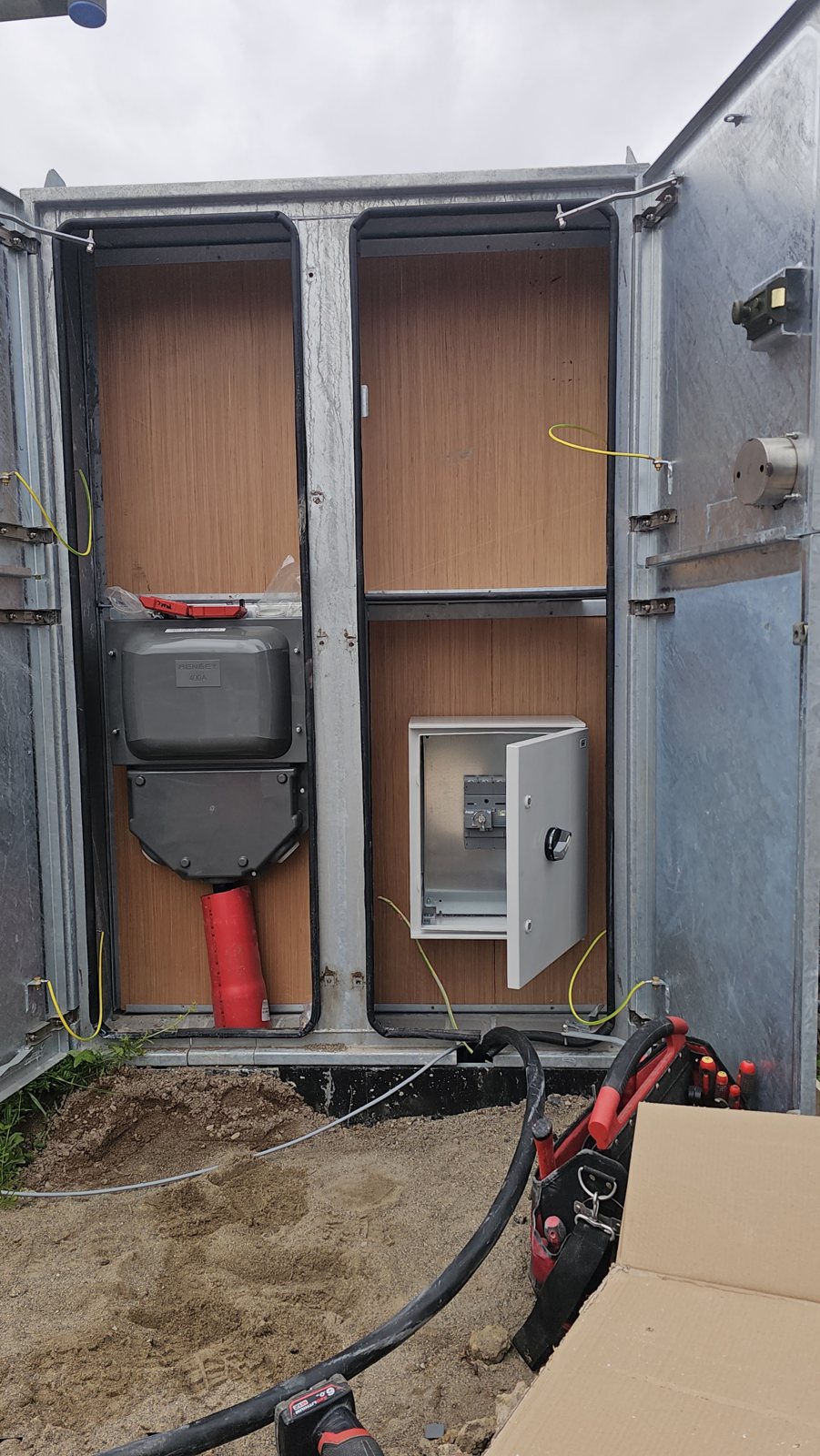 An outdoor electrical kiosk with its doors open during installation